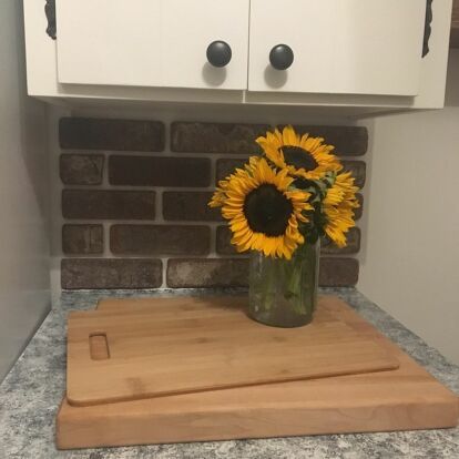 a vase with sunflowers sitting on a cutting board