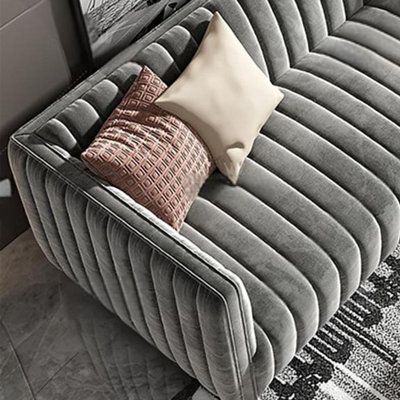 a grey couch with pillows on it in front of two pictures and a wall hanging