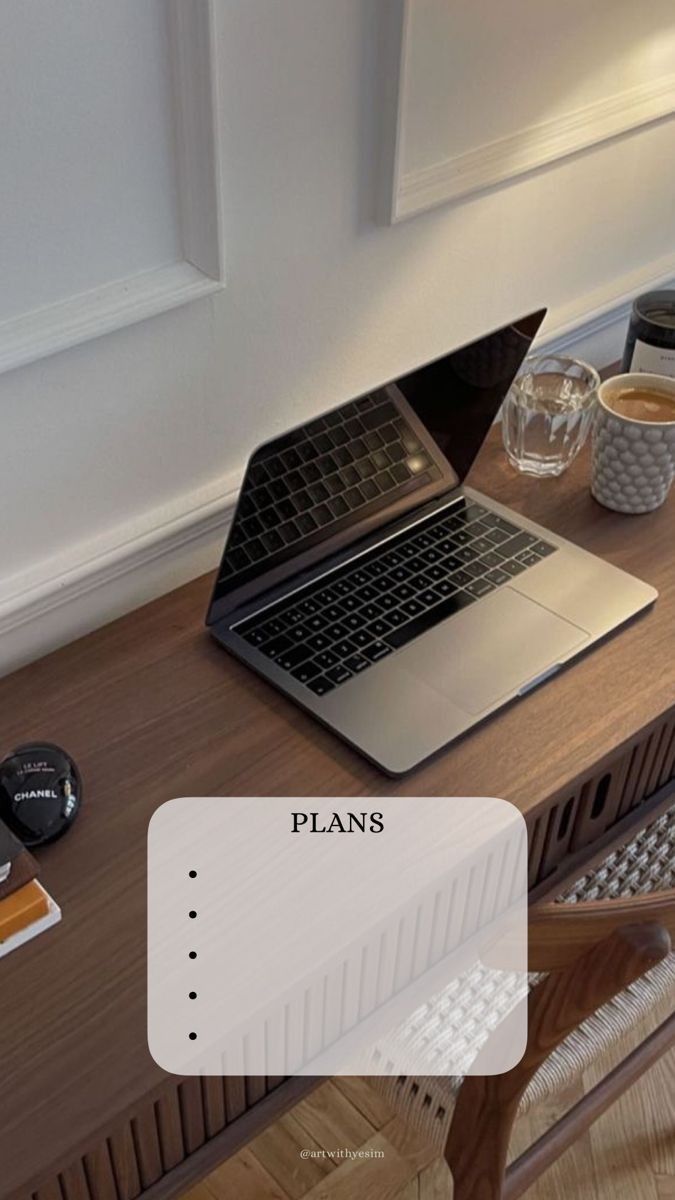 an open laptop computer sitting on top of a wooden desk next to a cup of coffee