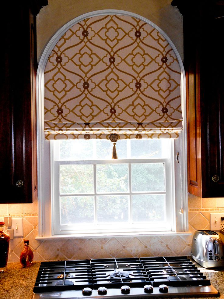 a kitchen with black cabinets and a window above the stove is decorated in an intricate pattern