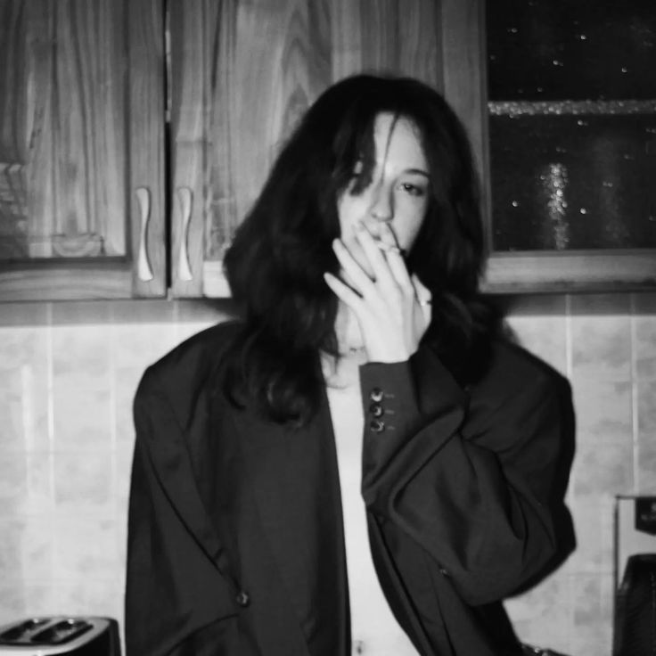 a black and white photo of a woman in the kitchen with her hand on her mouth