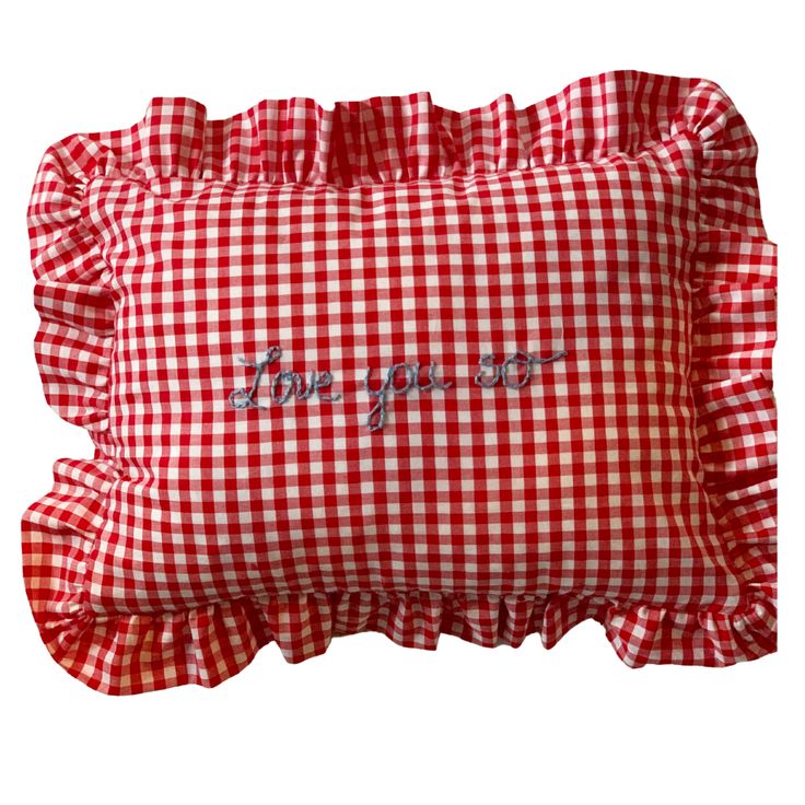 a red and white gingham pillow with the words love you more on it