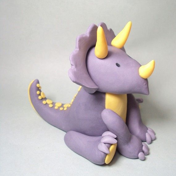 a purple toy with yellow horns and spikes on its head sits in front of a white background