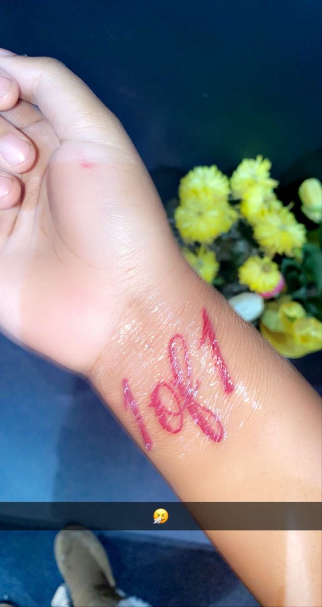 a woman's arm with the word love written on it and flowers in the background