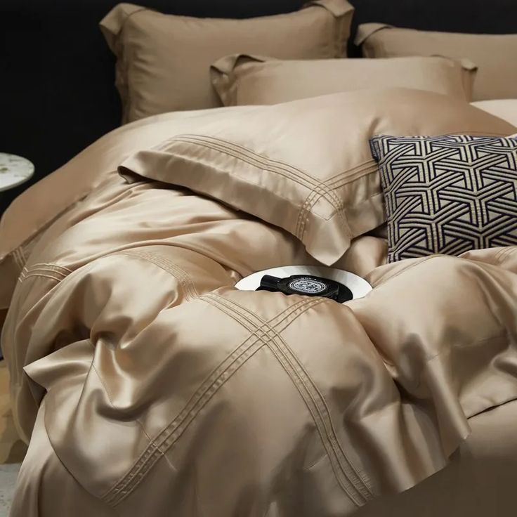 an unmade bed with beige sheets and pillows