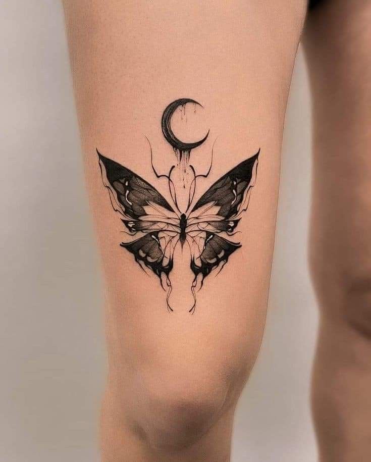 a woman's thigh with a butterfly tattoo on the leg and crescent moon behind it