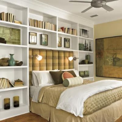 a bed sitting in a bedroom next to a white book shelf filled with lots of books