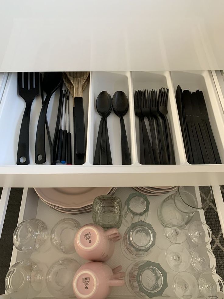 an open drawer with utensils and spoons in the bottom shelf, next to empty dishes