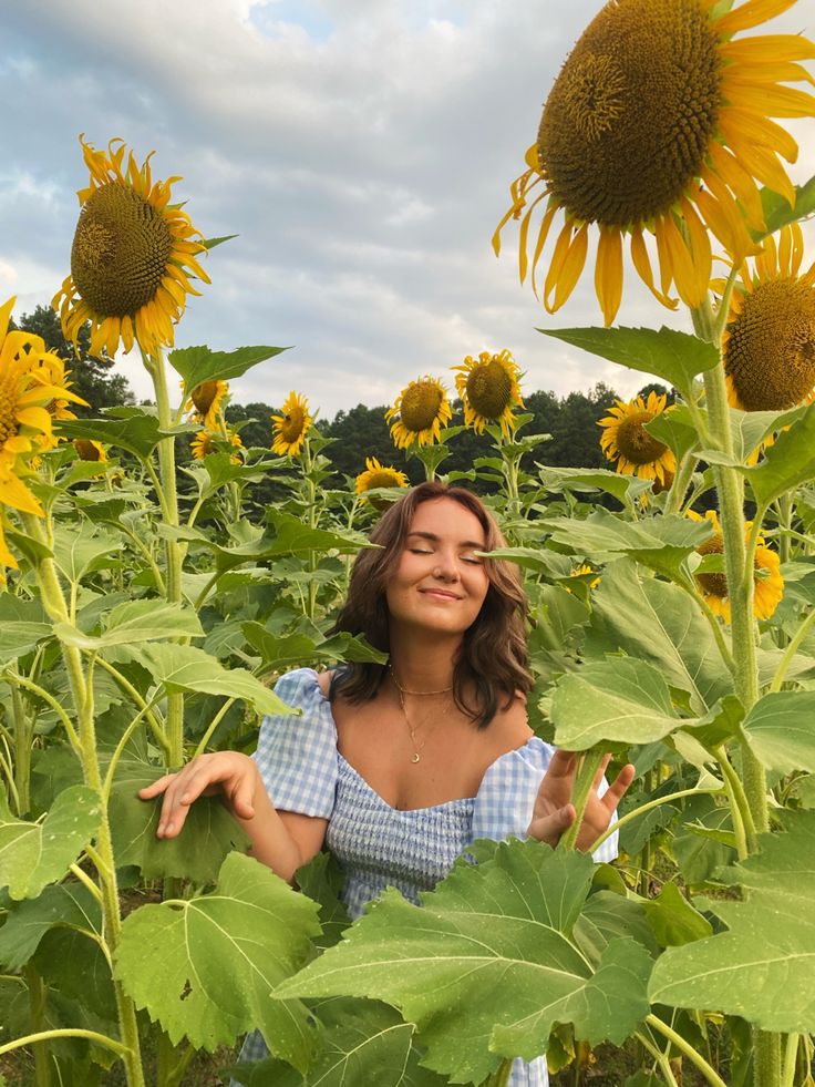 a woman standing in the middle of a sunflower field