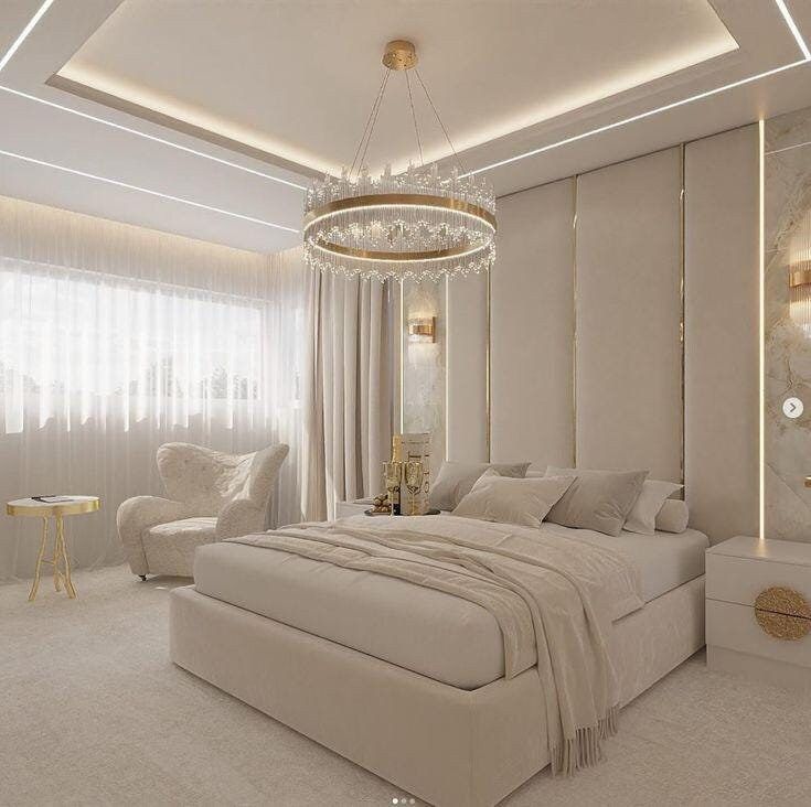 a large white bedroom with a chandelier hanging from the ceiling and two chairs