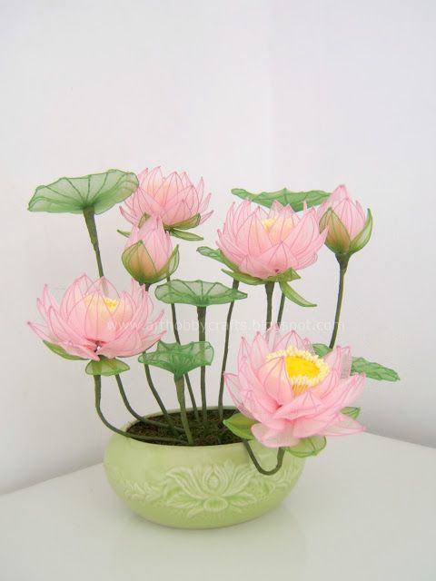 pink flowers are in a green vase on a white table top with water lilies