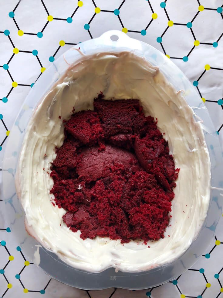 a red velvet cake with white frosting in a plastic container