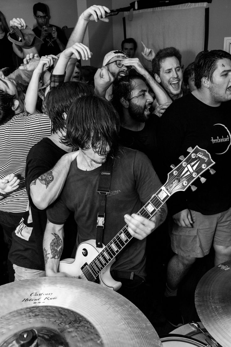 a group of men standing around each other with guitars and drums in front of them