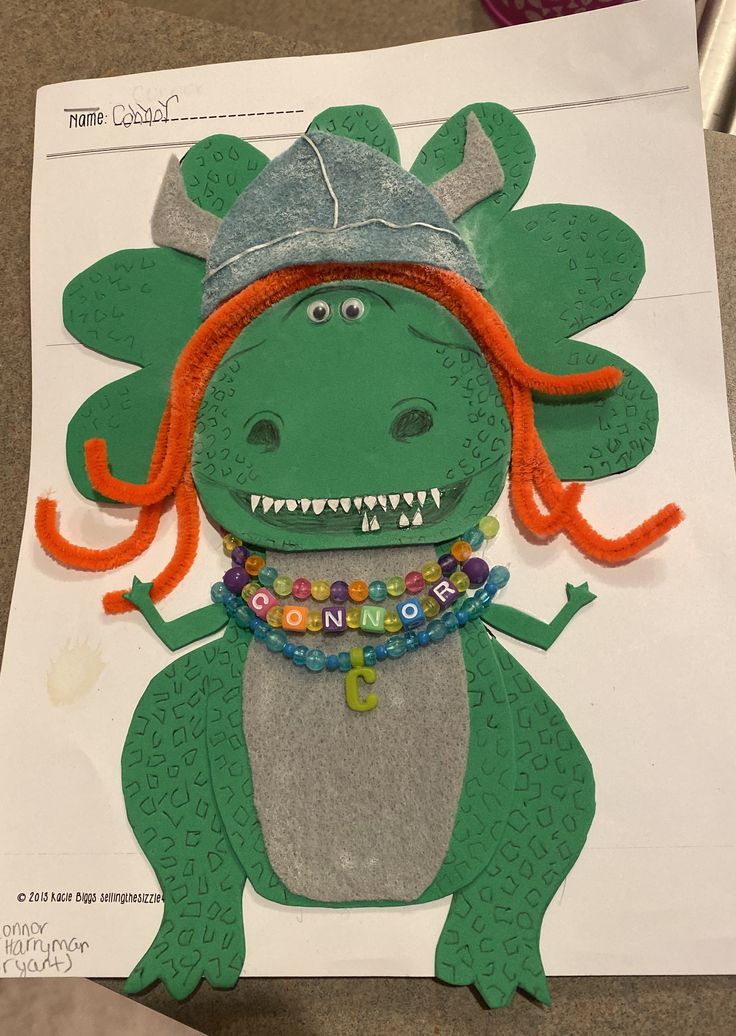 a paper cut out of a dinosaur wearing a hat and beads on it's neck