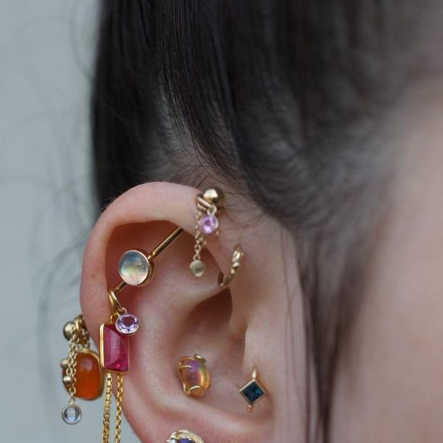 a woman wearing ear piercings with different colored stones