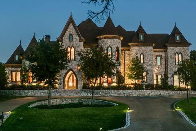 a large house with lots of windows and lights on it's front lawn area