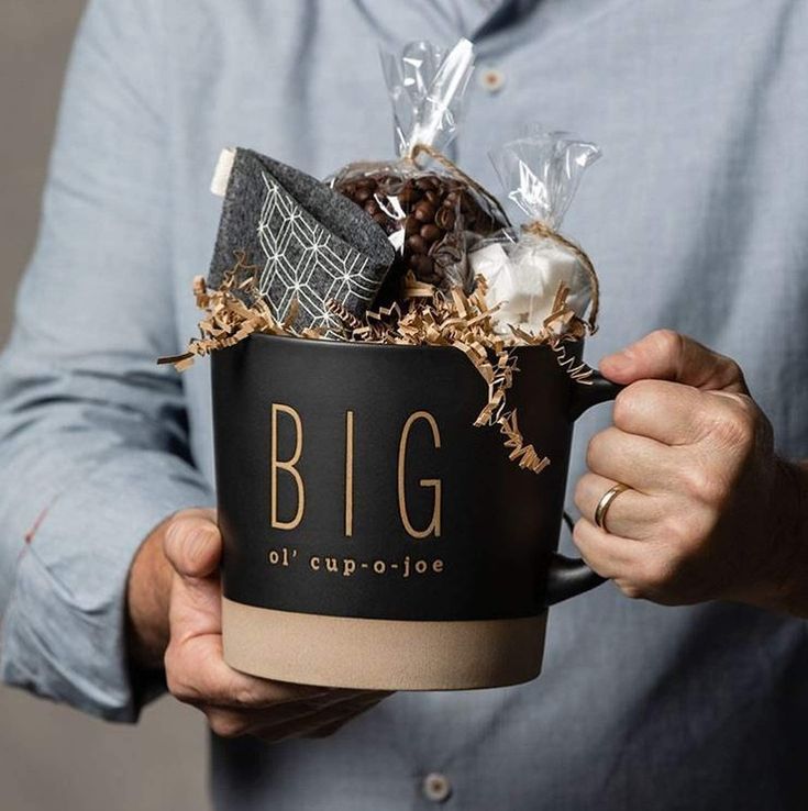 a man holding a coffee cup filled with chocolates