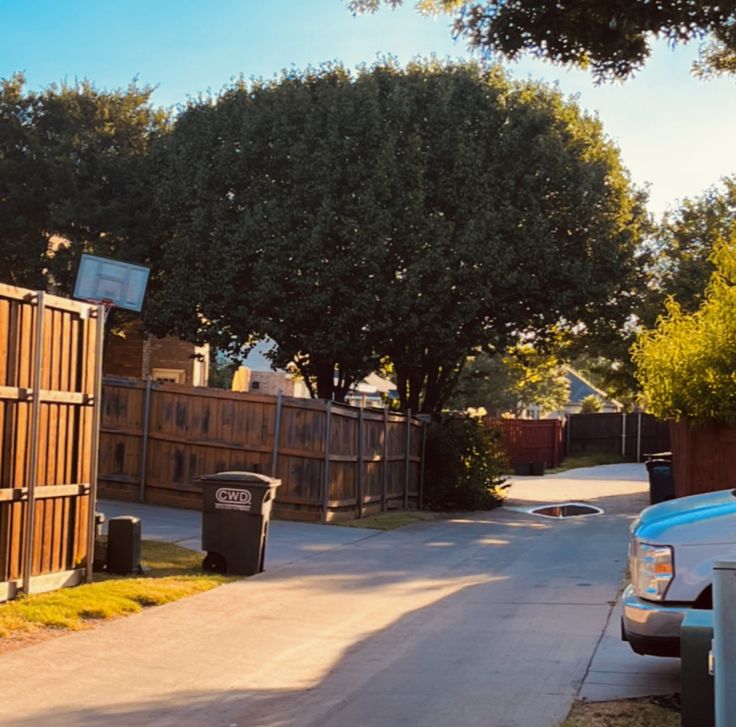 a blue truck parked on the side of a road next to a fence and trees