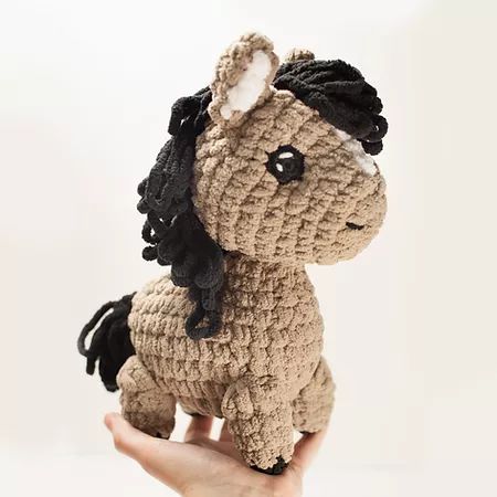 a hand holding a small crocheted pony