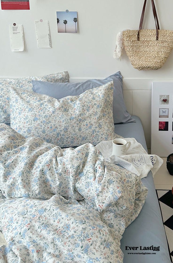 an unmade bed with blue and white sheets, pillows and pictures on the wall