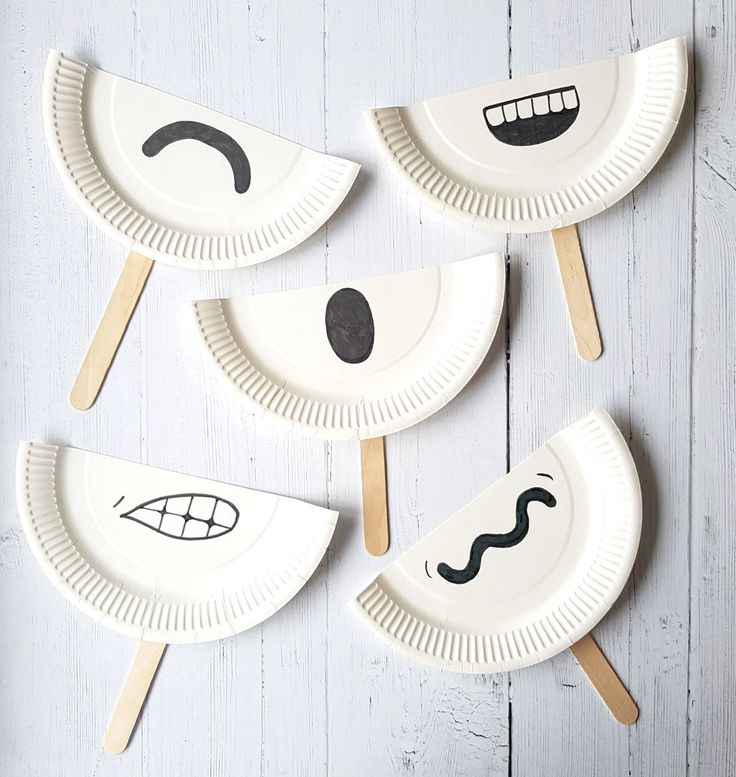 four paper plates with faces on them and sticks sticking out of the holes in each