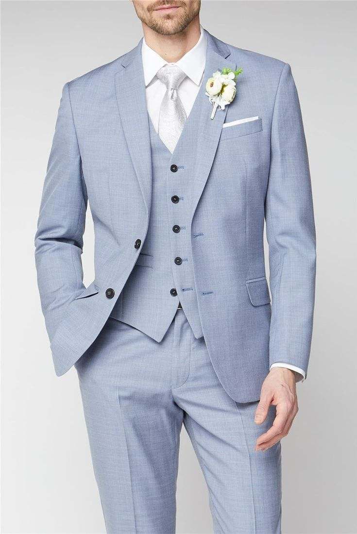 a man in a blue suit with a white boutonniere and flower on his lapel