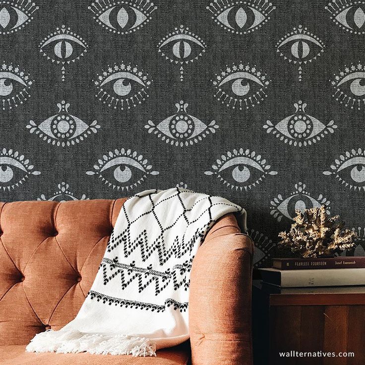 a brown couch sitting in front of a wallpaper with an eye pattern on it