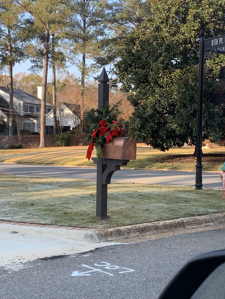 a mailbox with a wreath on it sitting in the middle of a street corner