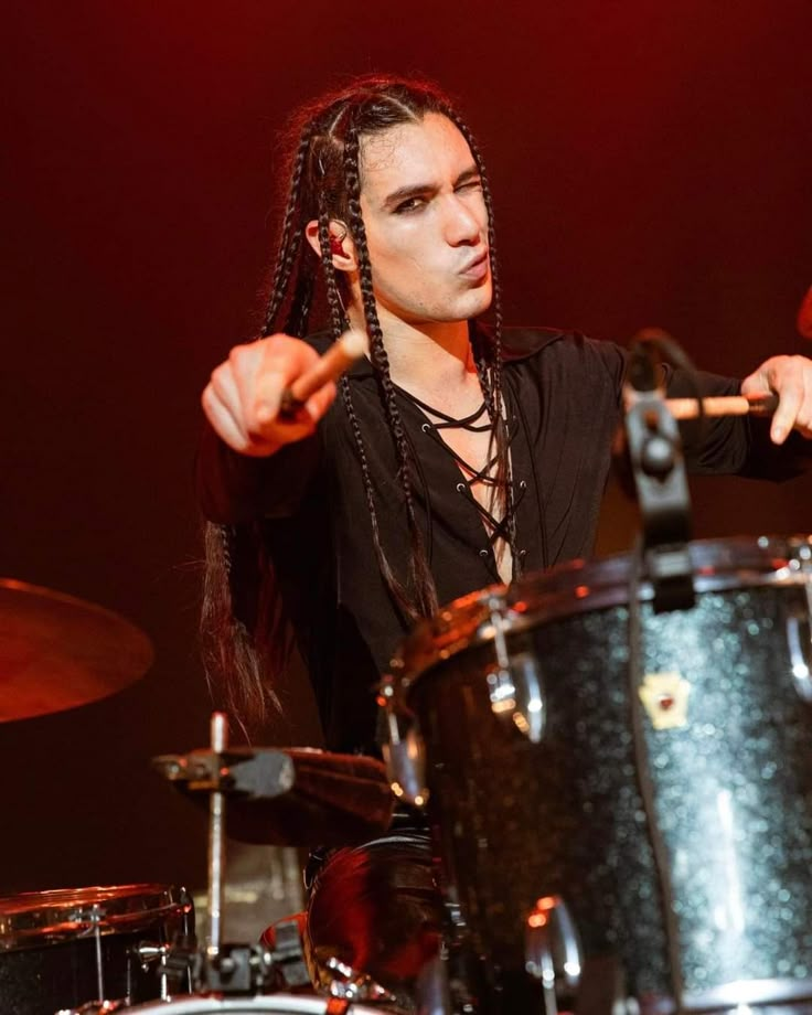 a man with dreadlocks playing drums on stage