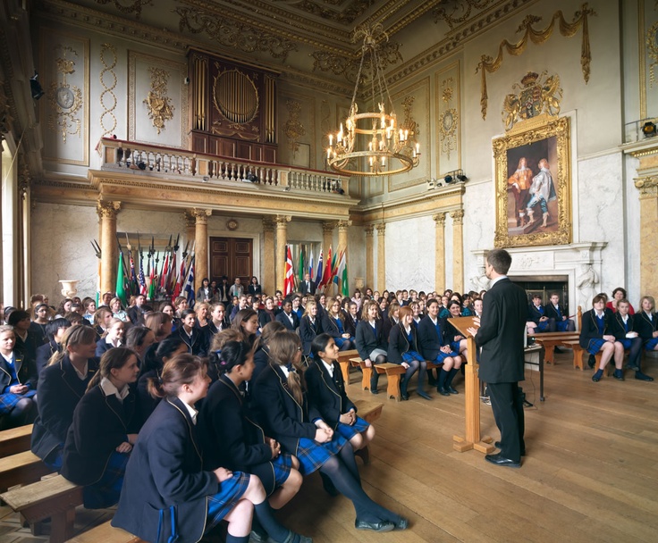 a large group of people sitting in front of a man giving a speech to them