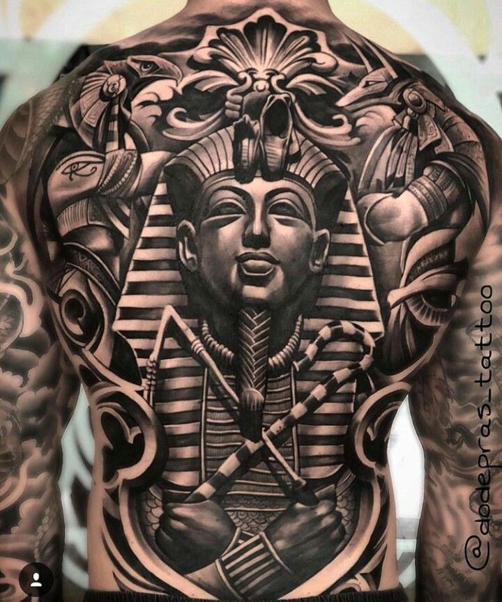 the back of a man's body with an egyptian tattoo design on his chest