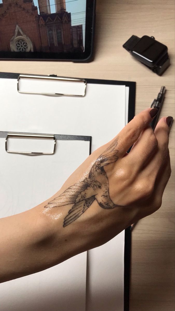 a woman's arm with a bird tattoo on it, next to a filing cabinet