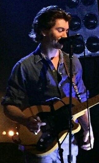 a man holding a guitar and singing into a microphone