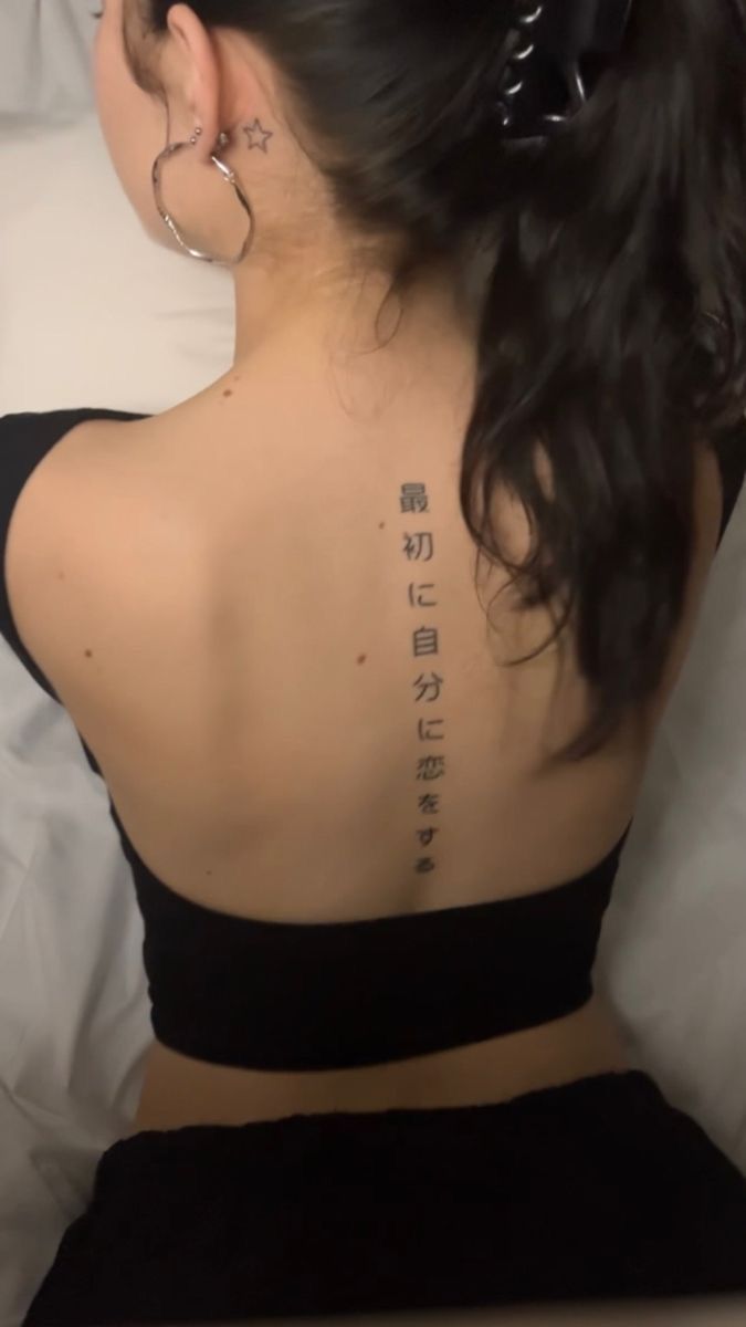 the back of a woman's neck with chinese writing on it and an ear piercing