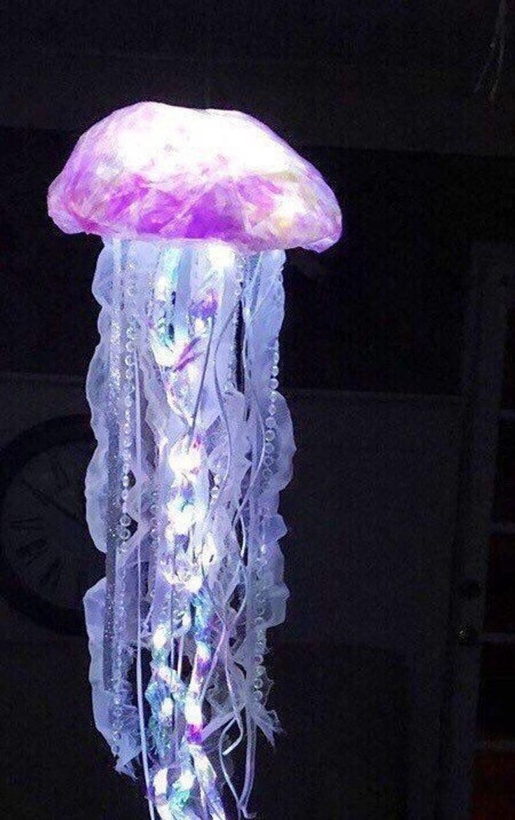 a purple jellyfish lamp is lit up in the dark with lights on it's sides