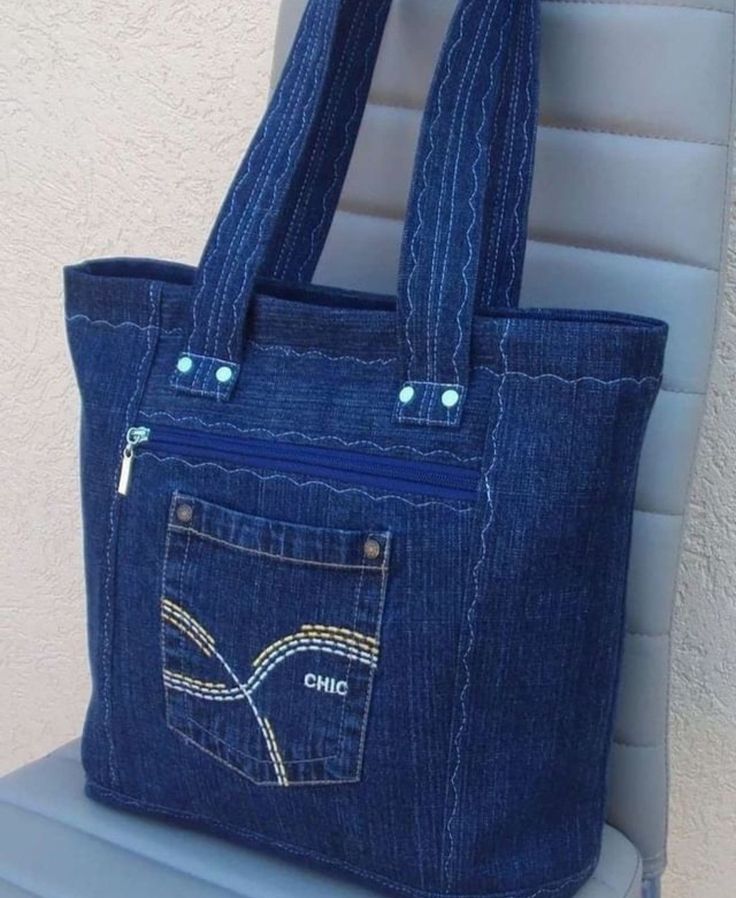 a denim purse with an embroidered pocket on the front and side, sitting on a chair