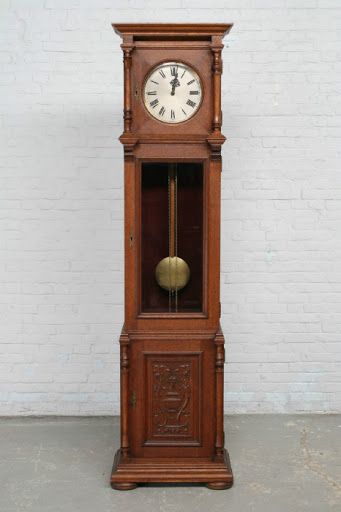 an old grandfather clock on display against a white brick wall