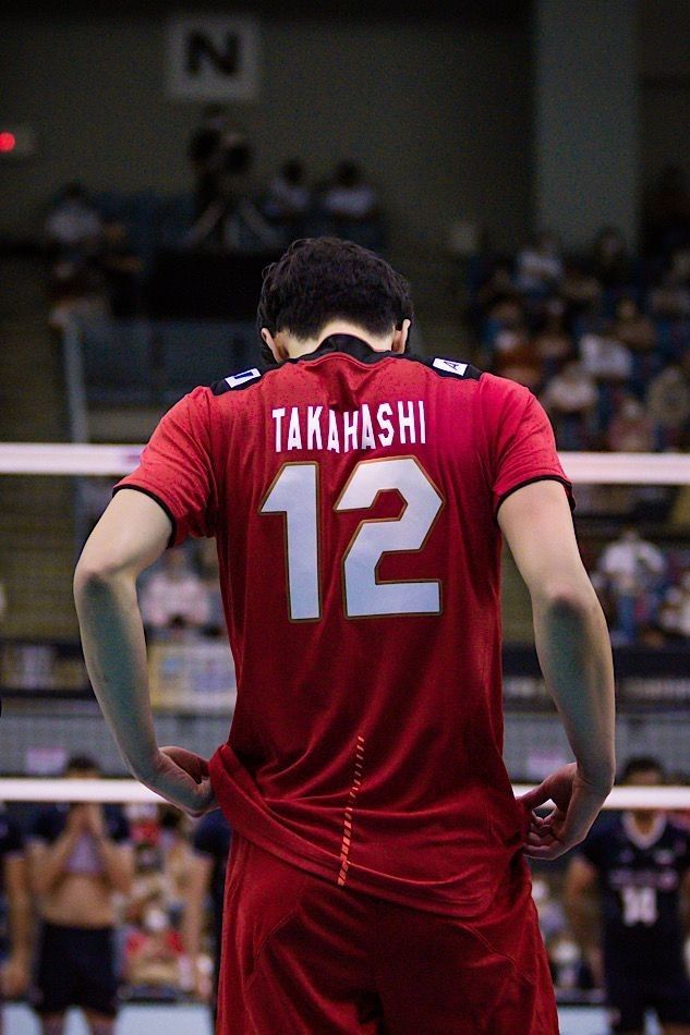 a volleyball player is standing in front of the net with his hands on his hips