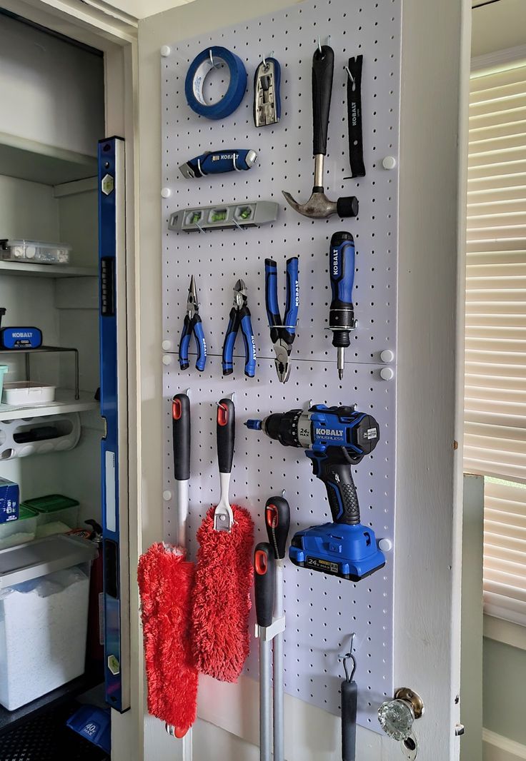 tools are hanging on the pegboard in this garage storage area, which is organized with white pegboards and blue trimmings