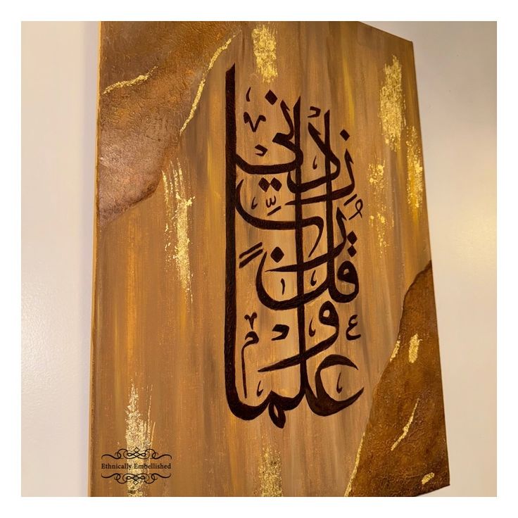 an arabic calligraphy is displayed on a wooden plaque with gold paint and metallic foil