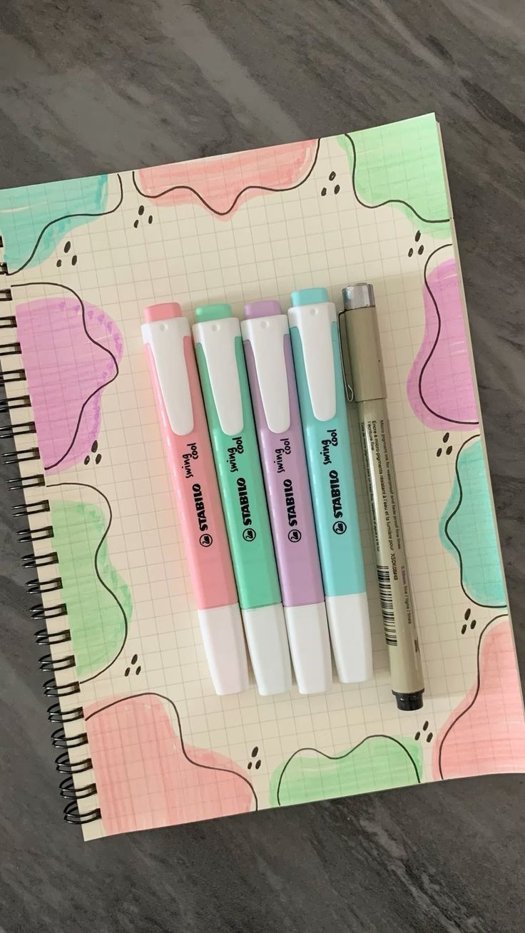 three pens sitting on top of a notebook