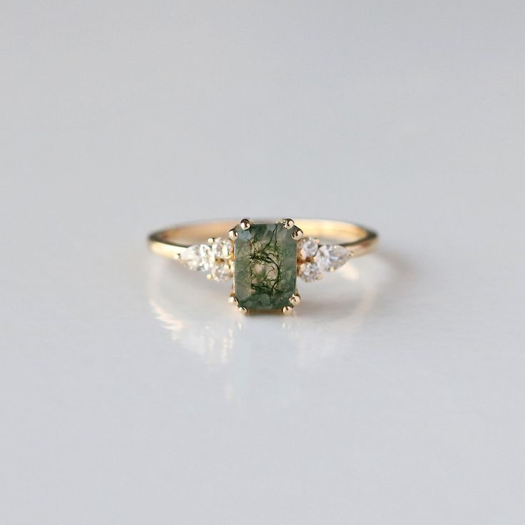 a gold ring with a green stone and three diamonds