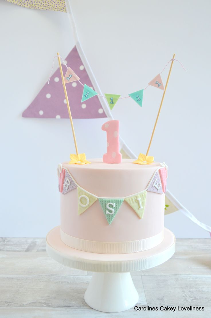 a pink cake decorated with flags and the number one