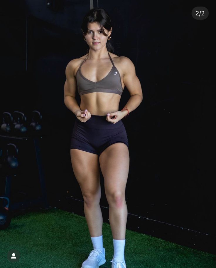 a woman standing on top of a lush green field with her hands in her pockets