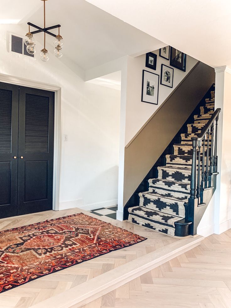 a staircase leading up to a black door with pictures on the wall and carpeted floor