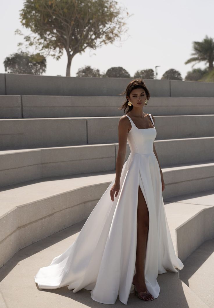 a woman in a white dress standing on some steps