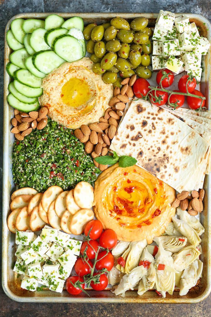 a platter filled with different types of food including bread, crackers and vegetables