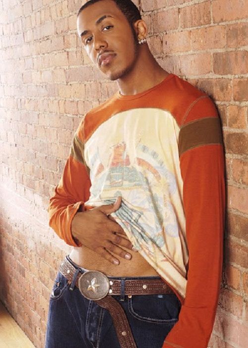 a young man leaning against a brick wall