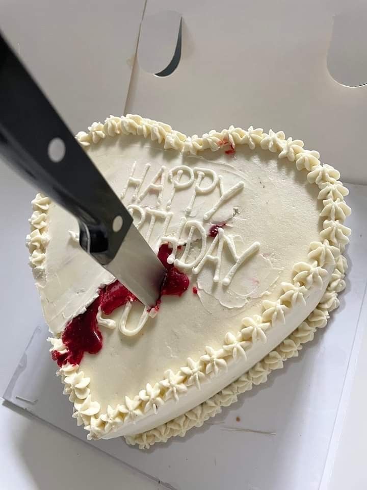 a heart shaped cake with the words happy birthday on it being cut by a knife