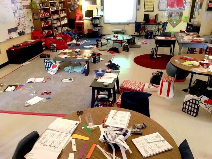 a classroom filled with desks and chairs covered in paper, pencils and markers